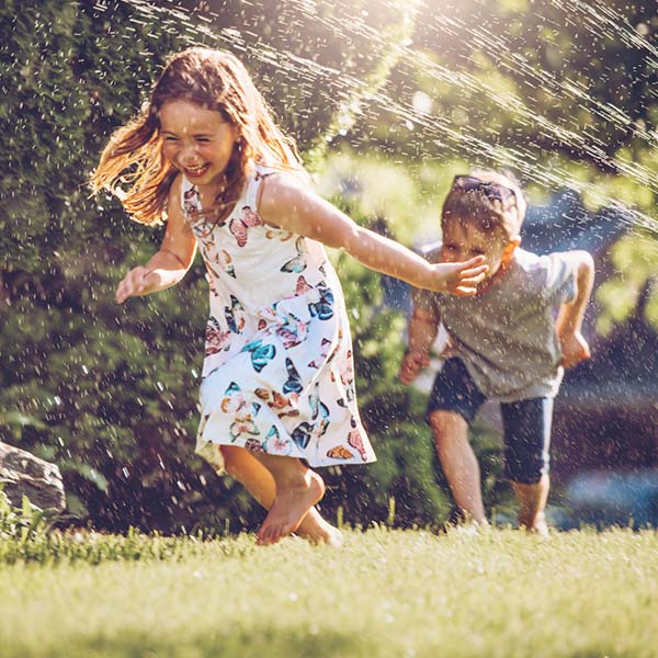 Happy kids playing with garden sprinkler